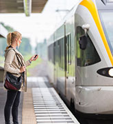 Eine Frau wartet am Gleis auf ihren Zug
