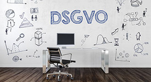 Zu sehen ist ein Arbeitsplatz und eine weiße Wand auf welcher "DSGVO" steht